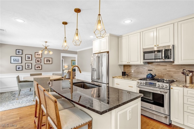 kitchen with pendant lighting, sink, stainless steel appliances, and a center island with sink