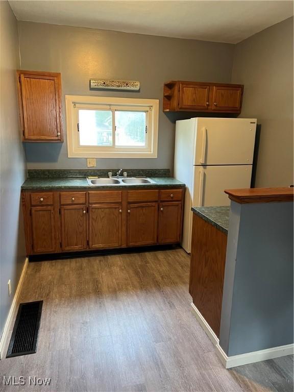 kitchen with white refrigerator, sink, and light wood-type flooring