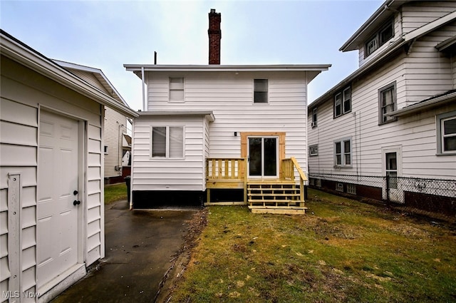 rear view of house featuring a wooden deck and a lawn