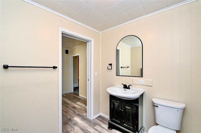 bathroom featuring hardwood / wood-style flooring, ornamental molding, vanity, and toilet