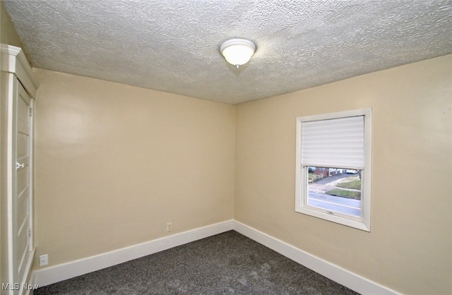 carpeted empty room featuring a textured ceiling