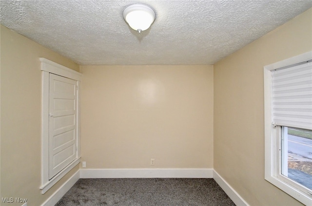 empty room with a textured ceiling and carpet flooring