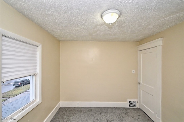 carpeted empty room with a textured ceiling