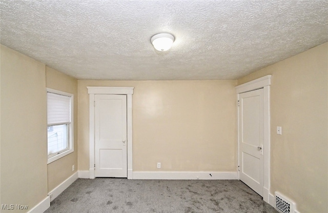 carpeted empty room featuring a textured ceiling