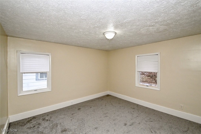 empty room with carpet floors and a textured ceiling