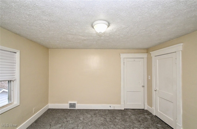 carpeted spare room with a textured ceiling