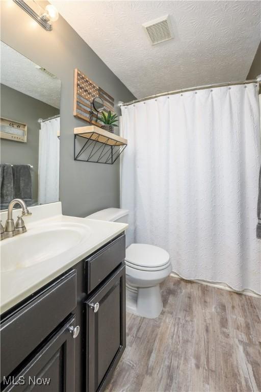1145 Cookhill Cir, Akron, OH 44312 - bathroom featuring a textured ceiling, toilet, visible vents, vanity, and wood finished floors