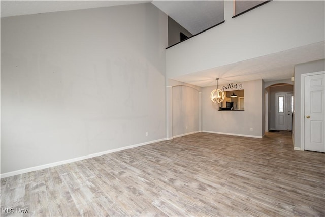 1145 Cookhill Cir, Akron, OH 44312 - interior space with wood finished floors, a towering ceiling, an inviting chandelier, arched walkways, and baseboards