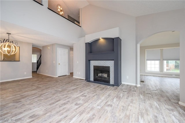 1145 Cookhill Cir, Akron, OH 44312 - unfurnished living room featuring an inviting chandelier, a tiled fireplace, wood finished floors, and arched walkways