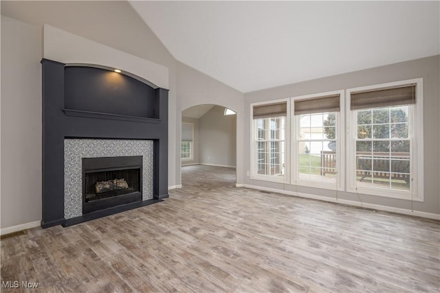 1145 Cookhill Cir, Akron, OH 44312 - unfurnished living room with wood finished floors, high vaulted ceiling, a fireplace, baseboards, and arched walkways