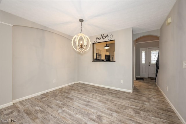1145 Cookhill Cir, Akron, OH 44312 - empty room featuring arched walkways, baseboards, a notable chandelier, and wood finished floors