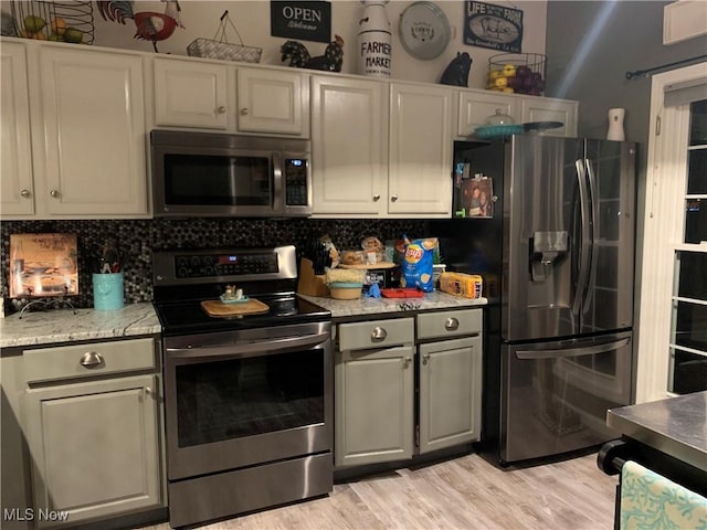 1145 Cookhill Cir, Akron, OH 44312 - kitchen with light wood finished floors, stainless steel appliances, decorative backsplash, and light stone counters