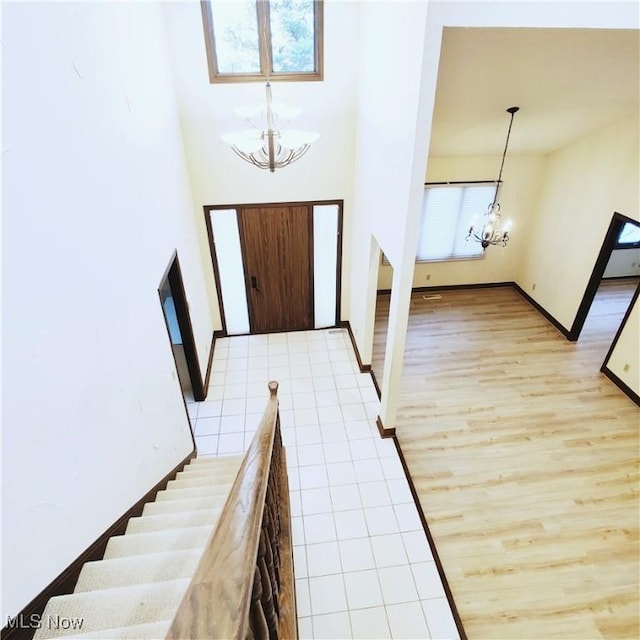 tiled foyer with a towering ceiling and a chandelier