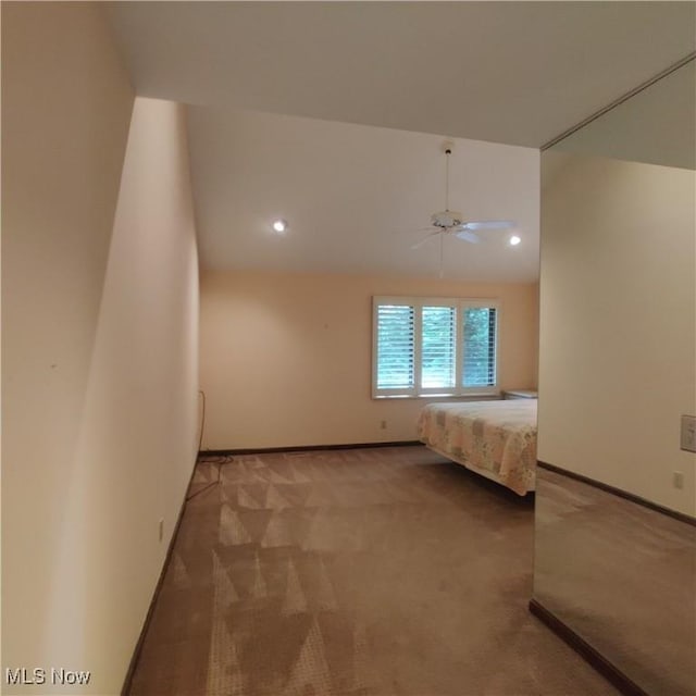 unfurnished bedroom with ceiling fan, lofted ceiling, and carpet flooring