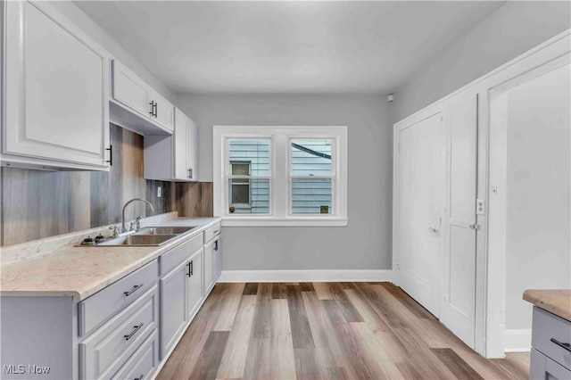 kitchen with white cabinetry, sink, and light hardwood / wood-style floors