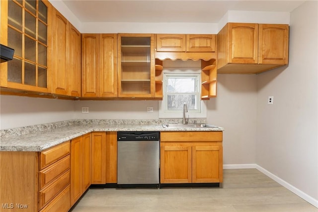 kitchen featuring dishwasher, sink, light stone counters, and light wood-type flooring