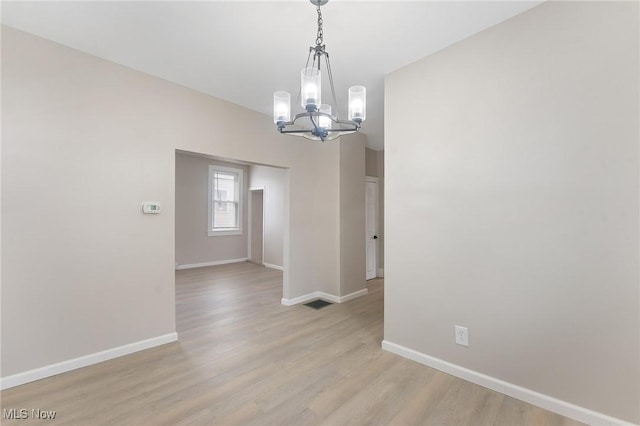 unfurnished room with a chandelier and light hardwood / wood-style flooring