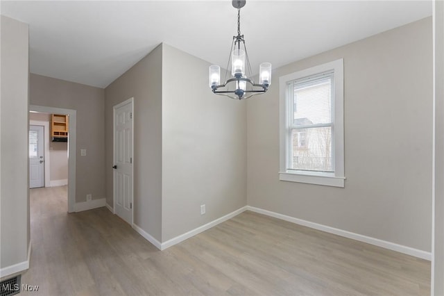 unfurnished dining area with light hardwood / wood-style floors and a notable chandelier