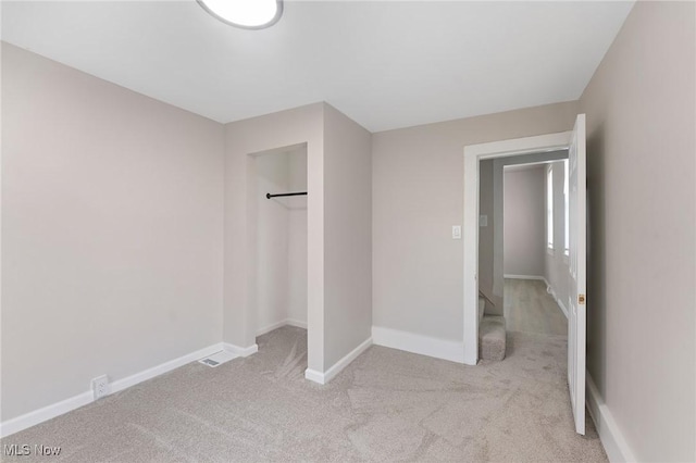 unfurnished bedroom with light colored carpet and a closet