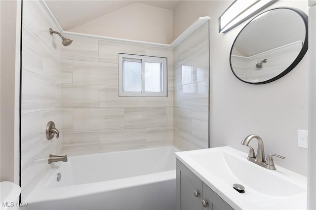 full bathroom featuring tiled shower / bath, lofted ceiling, toilet, and vanity