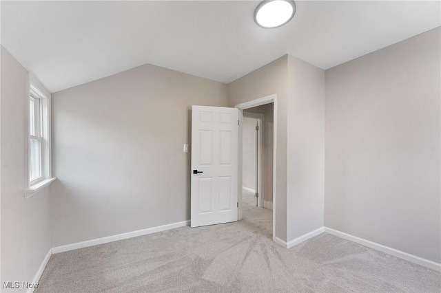 carpeted spare room with vaulted ceiling