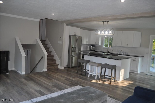 kitchen with stainless steel refrigerator with ice dispenser, a center island, hanging light fixtures, and white cabinets