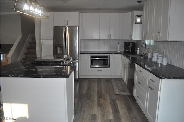 kitchen with sink, dark wood-type flooring, appliances with stainless steel finishes, hanging light fixtures, and white cabinets