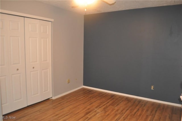 unfurnished bedroom featuring dark hardwood / wood-style flooring, a closet, and ceiling fan