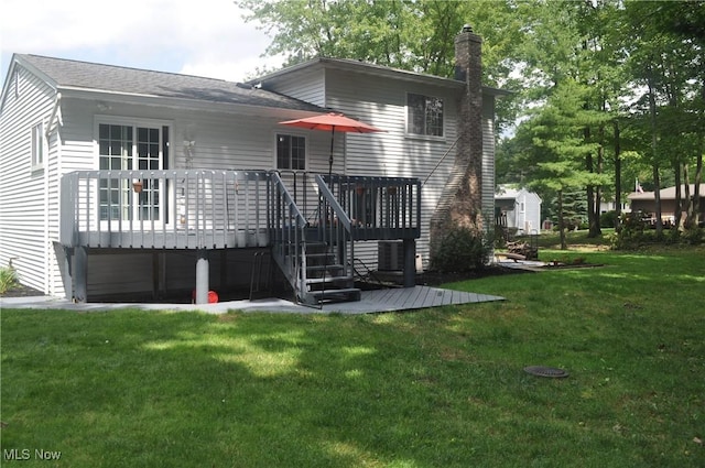 rear view of house with a wooden deck and a lawn