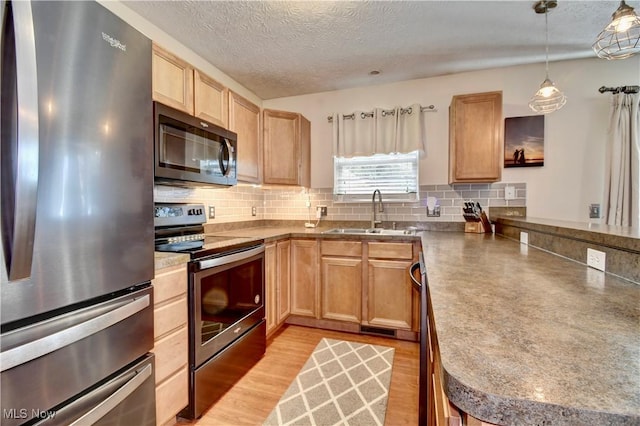 kitchen with sink, decorative light fixtures, appliances with stainless steel finishes, light hardwood / wood-style floors, and backsplash