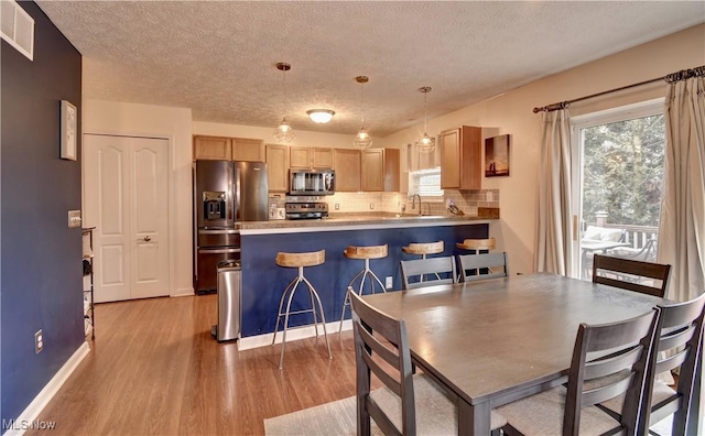 dining room featuring sink, light hardwood / wood-style flooring, and a textured ceiling