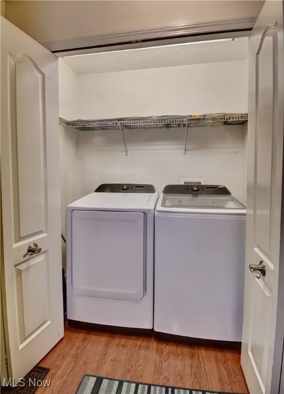 clothes washing area with independent washer and dryer and light hardwood / wood-style floors