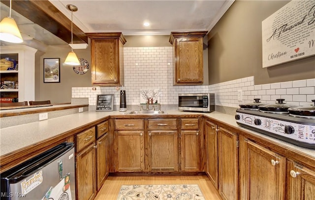 kitchen featuring pendant lighting, sink, backsplash, stainless steel appliances, and kitchen peninsula