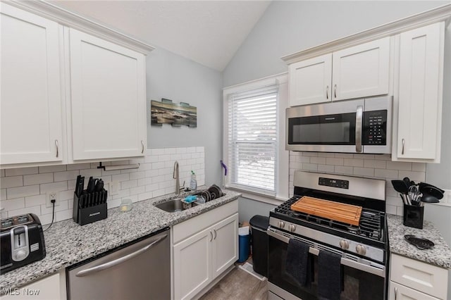 kitchen featuring stainless steel appliances, vaulted ceiling, and white cabinets