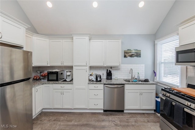 kitchen featuring lofted ceiling, stainless steel appliances, and white cabinets