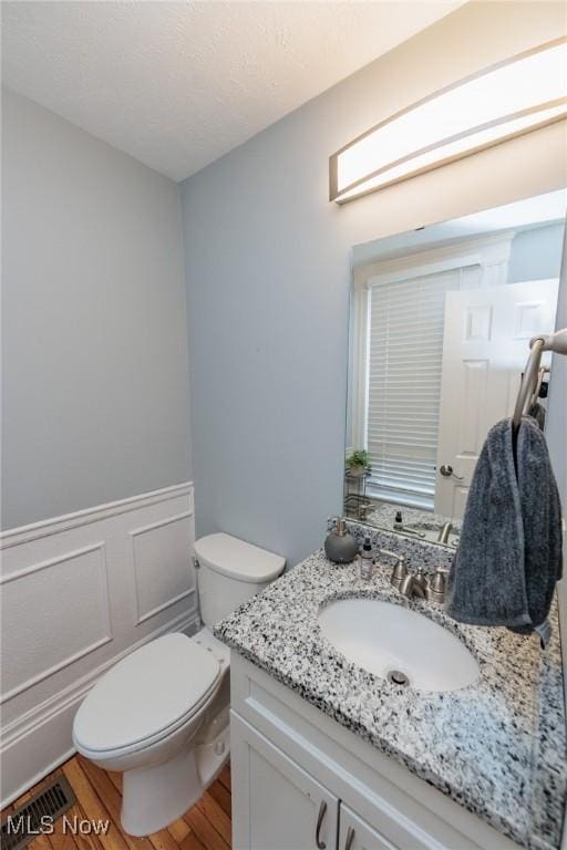 bathroom with vanity, toilet, and hardwood / wood-style floors