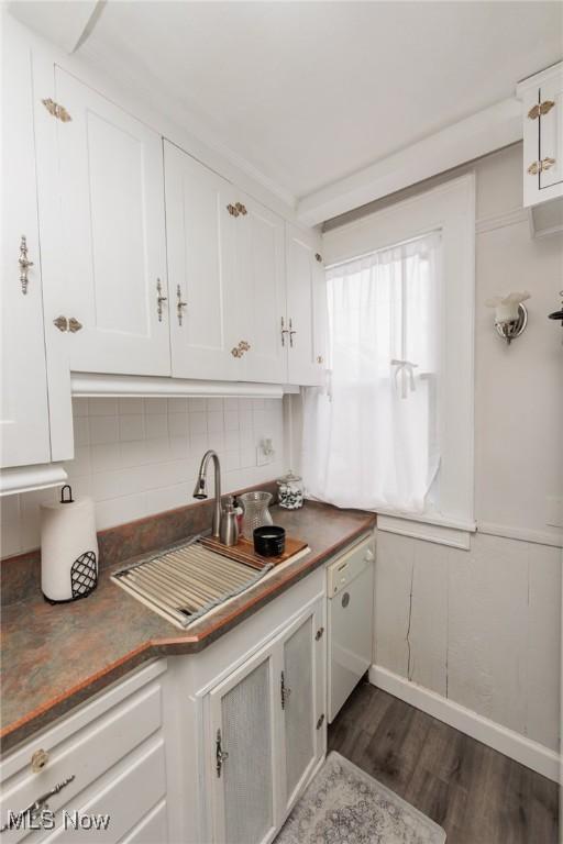 kitchen featuring sink, tasteful backsplash, dark hardwood / wood-style floors, white dishwasher, and white cabinets