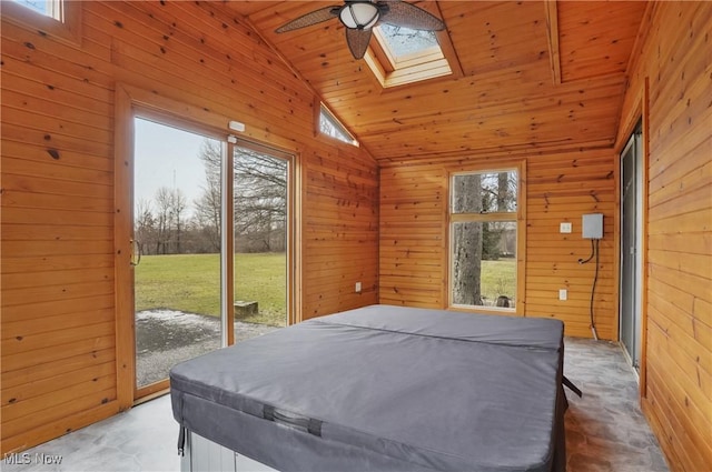 carpeted bedroom with ceiling fan, wood walls, lofted ceiling with skylight, and access to outside