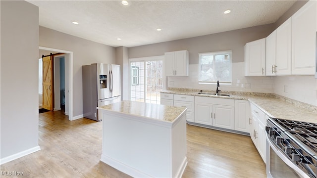 kitchen featuring sink, a center island, stainless steel appliances, a barn door, and white cabinets