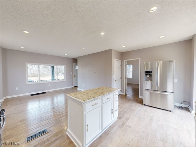 kitchen featuring light stone counters, white cabinets, light hardwood / wood-style floors, and stainless steel fridge with ice dispenser