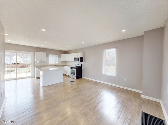 kitchen with appliances with stainless steel finishes, sink, a wealth of natural light, and white cabinets