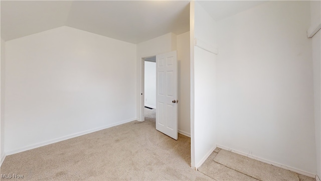 unfurnished room featuring lofted ceiling and light colored carpet