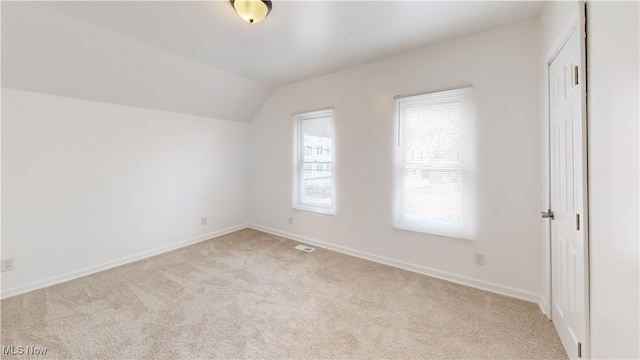 carpeted spare room featuring vaulted ceiling