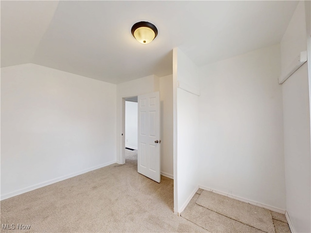 unfurnished bedroom featuring lofted ceiling and light carpet