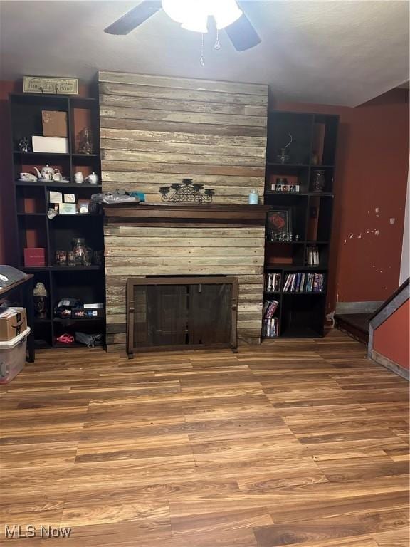 living room featuring ceiling fan, a fireplace, and wood-type flooring