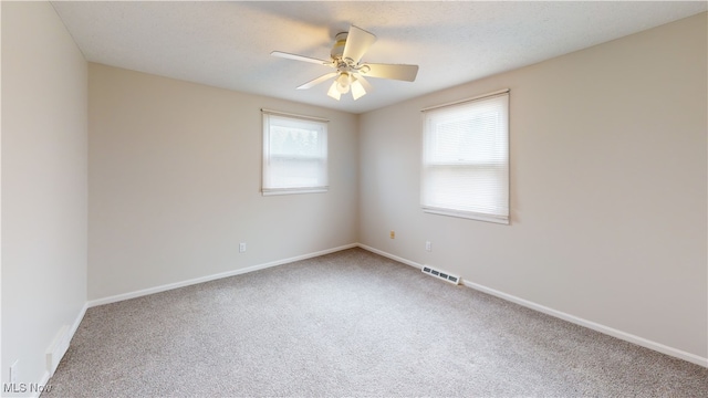 spare room with a textured ceiling, carpet floors, and ceiling fan