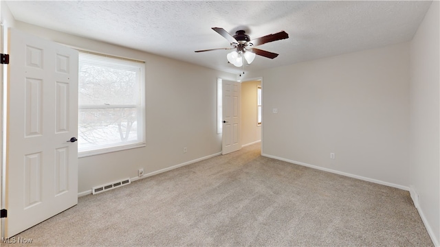 unfurnished room with light carpet, ceiling fan, and a textured ceiling