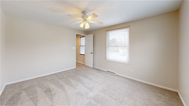 empty room featuring ceiling fan, light carpet, and a textured ceiling