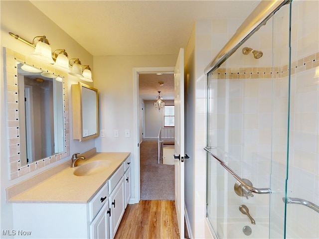 bathroom featuring vanity, wood-type flooring, and combined bath / shower with glass door