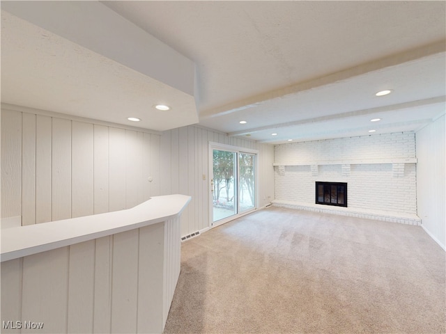 interior space featuring beam ceiling, light carpet, and a brick fireplace